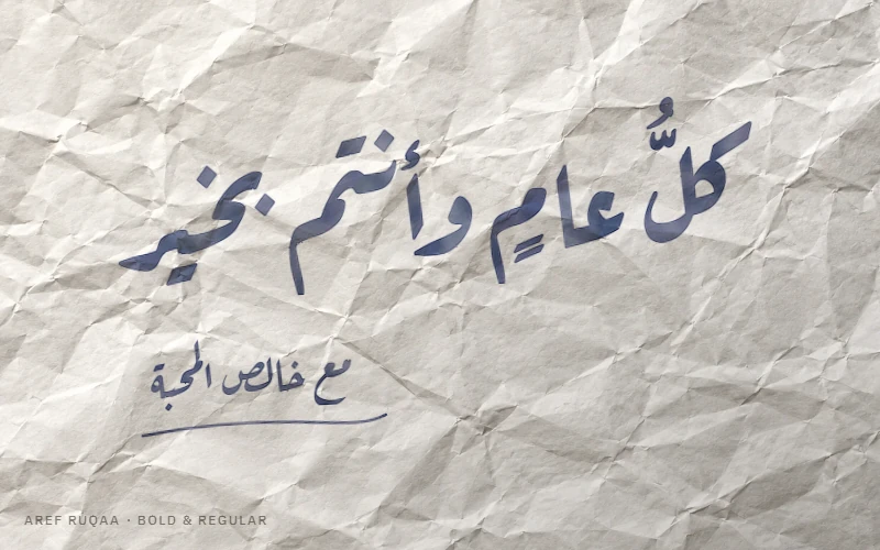 عبارة «كل عام وأنتم بخير» بحبر أزرق داكن بخط رقعة عارف على ورقة مجعّدة، وتحتها «مع خالص المحبة»
